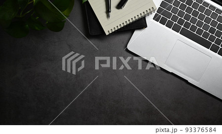 Top view laptop computer, notepad and pen on dark stone background with copy space. Modern workspace Top view laptop computer, notepad and pen on dark stone background with copy space. Modern workspace 93376584