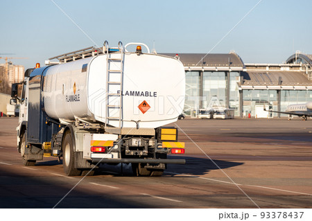 Back view small modern fuel tanker truck driving on airfield taxiway for aircraft refueling. Cistern lorry aviation gasoline. Plane gas supply. Airport maintenance handling service vehicle equipment 93378437