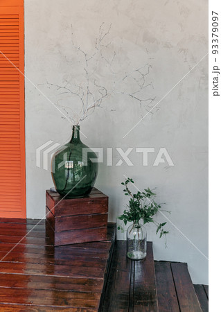 Green vase with leaves near gray wall 93379097