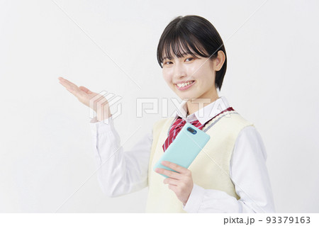 白背景でスマホを持って左を手のひらで指す女子高生 白背景でスマホを持って左を手のひらで指す女子高生 93379163