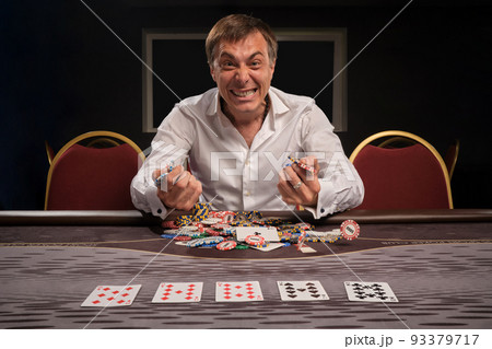 Handsome emotional man is playing poker sitting at the table in casino. Handsome emotional man is playing poker sitting at the table in casino. 93379717