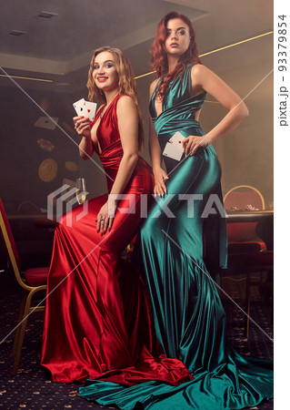 Two beautiful women are posing against a poker table in luxury casino. Two beautiful women are posing against a poker table in luxury casino. 93379854