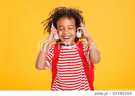 Modern funny ethnic schoolboy listening to music in headphones Modern funny ethnic schoolboy listening to music in headphones 93380309