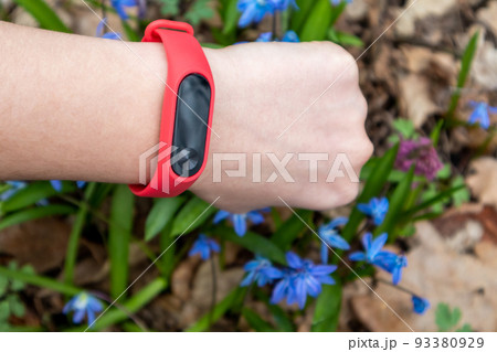 Fitness tracker, red band on wrist in blue flowers Fitness tracker, red band on wrist in blue flowers 93380929