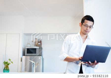 ダイニングで立ちながらパソコンを操作する男性 ダイニングで立ちながらパソコンを操作する男性 93382110