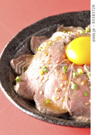 生卵の黄身と万能ねぎ、白胡麻が乗っているローストビーフ丼 生卵の黄身と万能ねぎ、白胡麻が乗っているローストビーフ丼 93383726