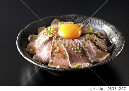 生卵の黄身と万能ねぎ、白胡麻が乗っているローストビーフ丼を黒背景で撮影 生卵の黄身と万能ねぎ、白胡麻が乗っているローストビーフ丼を黒背景で撮影 93384207