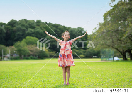 晴れた公園で両手を広げる笑顔の少女 晴れた公園で両手を広げる笑顔の少女 93390431