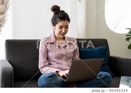 Smiling asian young woman working on laptop at home office. Young asian student using computer remote studying, virtual training, e-learning, watching online education webinar at house Smiling asian young woman working on laptop at home office. Young asian student using computer remote studying, virtual training, e-learning, watching online education webinar at house 93391334