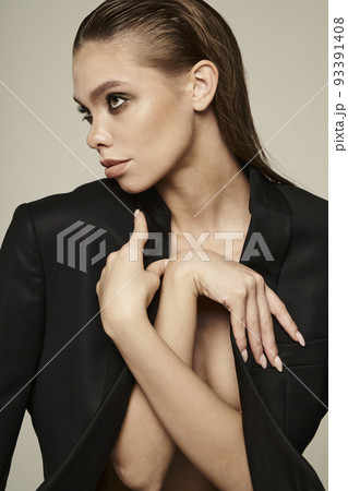 Fashion portrait of a beautiful young woman posing in a black evening suit Fashion portrait of a beautiful young woman posing in a black evening suit 93391408