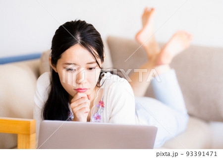 自宅のソファで寛ぐ若い女性 自宅のソファで寛ぐ若い女性 93391471