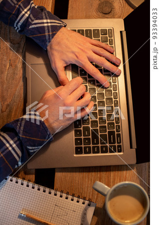Young man drinking coffee in cafe and using laptop. Man's hands using laptop during coffee break Young man drinking coffee in cafe and using laptop. Man's hands using laptop during coffee break 93394033