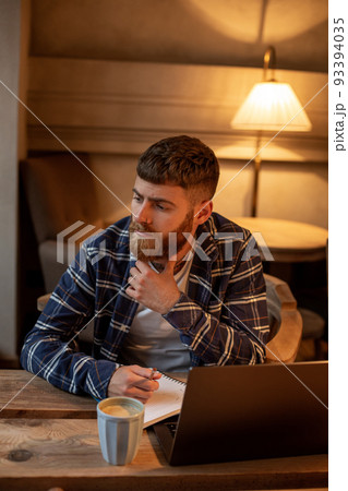 Casual business man or freelancer planning his work on notebook, working on laptop computer with smart phone, cup of coffee on table at coffee shop or home office. Casual business man or freelancer planning his work on notebook, working on laptop computer with smart phone, cup of coffee on table at coffee shop or home office. 93394035