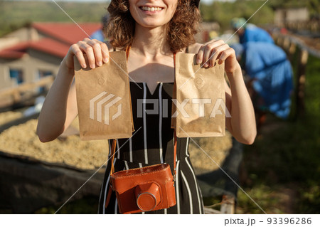 Smiling woman holding two paper bags with coffee beans 93396286