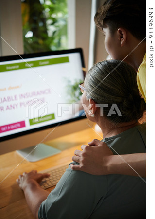 Teenage boy helping grandmother with ordering insurance policy online Teenage boy helping grandmother with ordering insurance policy online 93396993