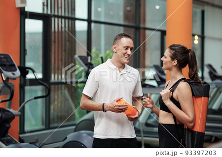 Smiling sportswoman talking to her trainer in gym 93397203