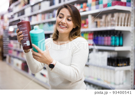 Young Latina choosing haircare cosmetics in specialized boutique Young Latina choosing haircare cosmetics in specialized boutique 93400541