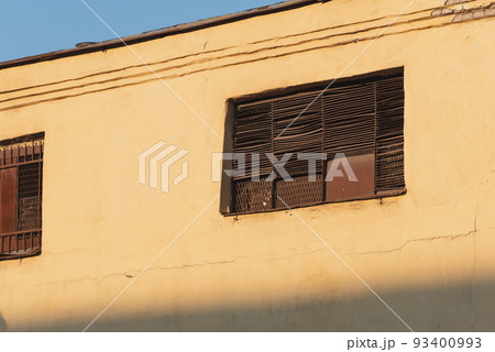 Yellow wall of an old factory with rusty iron shutters on windows Yellow wall of an old factory with rusty iron shutters on windows 93400993