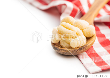 Uncooked potato gnocchi in wooden spoon isolated on white background. Uncooked potato gnocchi in wooden spoon isolated on white background. 93401499