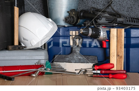 In celebration of Labor Day, a white protective construction helmet and a variety of construction tools are assembled on a wooden table. In celebration of Labor Day, a white protective construction helmet and a variety of construction tools are assembled on a wooden table. 93403175