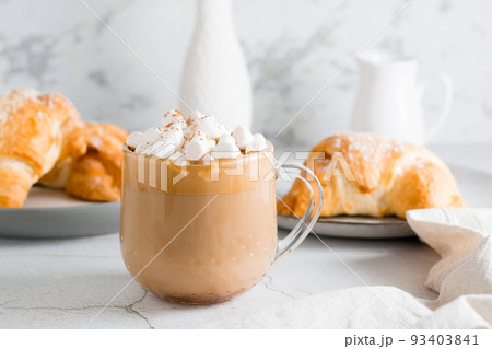 Delicious coffee with marshmallows and croissants on plates on the table. Lifestyle homemade snack. Close-up Delicious coffee with marshmallows and croissants on plates on the table. Lifestyle homemade snack. Close-up 93403841