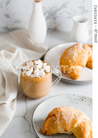 Cup of coffee with marshmallows and croissants on plates on the table. Homemade breakfast lifestyle. Vertical view 93403842
