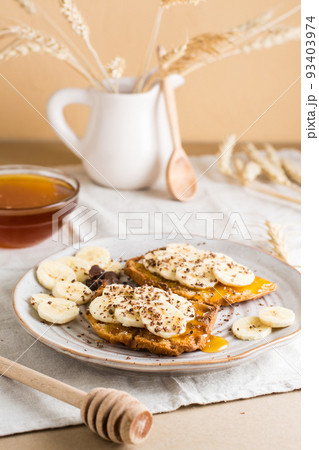 Ready to eat sandwiches with honey, banana and chocolate on a plate on the table. Homemade vegetarian snack. Vertical view Ready to eat sandwiches with honey, banana and chocolate on a plate on the table. Homemade vegetarian snack. Vertical view 93403974