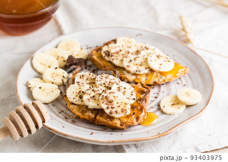 Ready to eat bruschettas with honey, banana and chocolate on a plate on the table. Vegetarian homemade snack. Close-up Ready to eat bruschettas with honey, banana and chocolate on a plate on the table. Vegetarian homemade snack. Close-up 93403975
