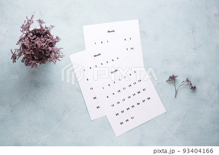 Clean sheets of a monthly calendar and a bouquet of dried flowers on the table. Time planning and organization 93404166