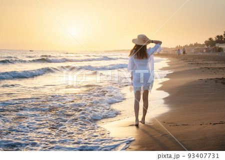 Beautiful young woman with straw hat in white dress on the sea 93407731