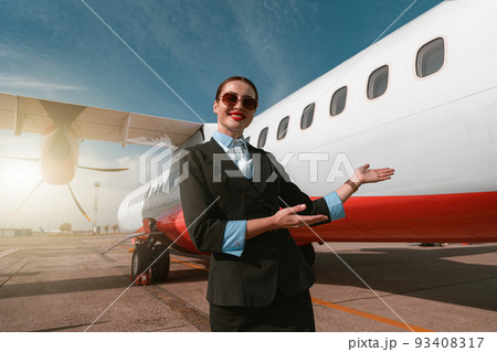 Woman stewardess standing near airplane and inviting on board 93408317