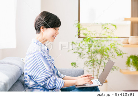リビングでノートパソコンを使う若い女性 リビングでノートパソコンを使う若い女性 93410891