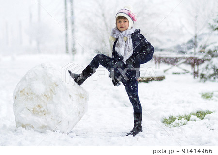Little girl outdoors in winter near big snow ball 93414966