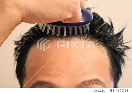 ヘアブラシで頭皮をマッサージする男性 ヘアブラシで頭皮をマッサージする男性 93416213