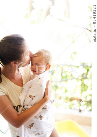 Mom kisses a whimpering baby holding him in her arms Mom kisses a whimpering baby holding him in her arms 93419321