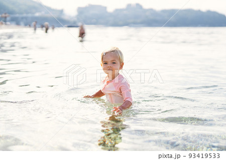 Little girl stands in the sea in shallow Little girl stands in the sea in shallow 93419533