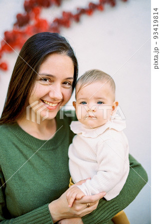 Smiling mother with a baby in her arms. Portrait 93419814