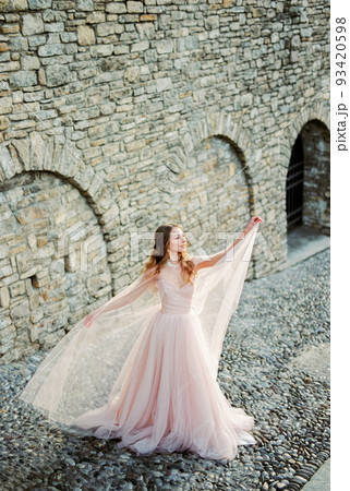 Bride stands near the stone wall on the street of Bergamo. Italy Bride stands near the stone wall on the street of Bergamo. Italy 93420598