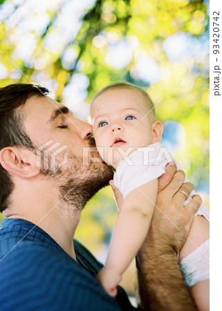 Dad kisses the baby, lifting him in his arms. Portrait Dad kisses the baby, lifting him in his arms. Portrait 93420742
