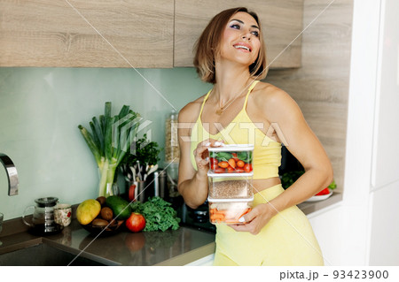 A smiling girl holds containers of fresh vegetables in her hands. 93423900