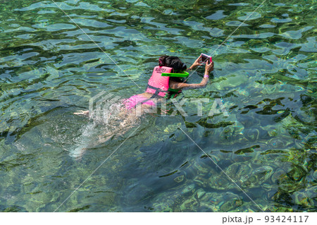 Girl wearing life jacket snorkeling in ocean clear water Girl wearing life jacket snorkeling in ocean clear water 93424117