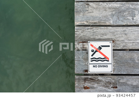 No Diving sign on a pier floor with ocean water in the background 93424457