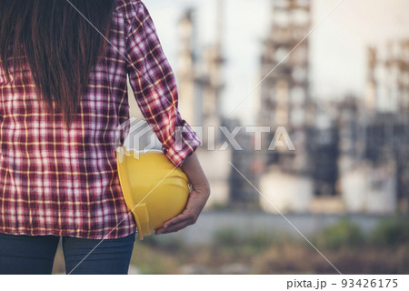 Woman worker hands holding hardhat yellow work helmet Construction Engineer. Refinery woman worker oil petro industry hand hold yellow worker helmet hard hat. Refinery industry engineer manufacture 93426175