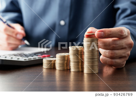 収入と支出の計算し、資金を節約する。積まれたコインと電卓。帳簿をつける人。 93426769