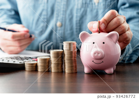 節約のイメージ。ブタの貯金箱にコインを入れる。お金を貯める。収入と支出の計算。 93426772