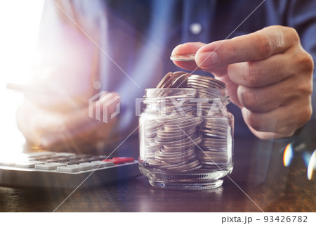 節約のイメージ。ガラスのビンにコインを入れる。収入と支出の計算。 節約のイメージ。ガラスのビンにコインを入れる。収入と支出の計算。 93426782