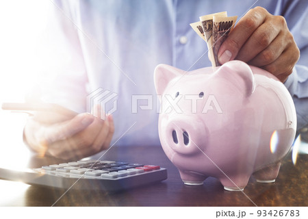 節約のイメージ。ブタの貯金箱にコインを入れる。収入と支出の計算。 節約のイメージ。ブタの貯金箱にコインを入れる。収入と支出の計算。 93426783