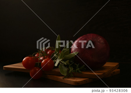 A beautiful branch of ripe cherry tomatoes, a red onion and fresh greens  93428306
