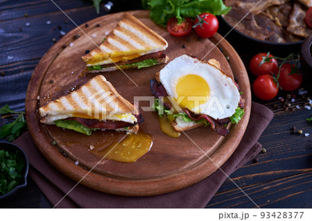 French toasts with fried eggs, cream cheese, salad and bacon 93428377