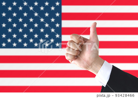 アメリカ国旗の前でサムアップするビジネスマンの手元 93428466